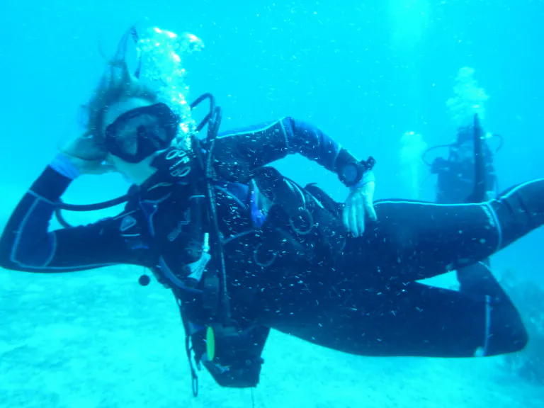 Person scuba diving underwater, surrounded by blue ocean.
