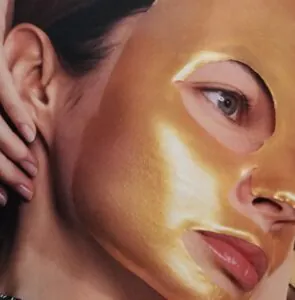 Close-up of a woman wearing a shiny gold facial mask. Close-up of a woman wearing a shiny gold facial mask.