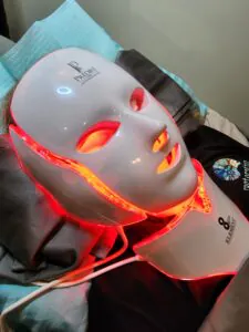 LED light therapy mask glowing in red on a surface. LED light therapy mask glowing in red on a surface.