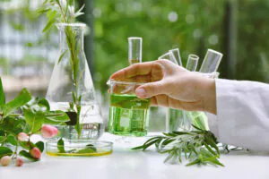 Scientist handling green liquid in a laboratory with plants around.