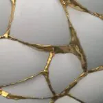 Close-up of white ceramic pieces joined by gold lacquer in a kintsugi style. Close-up of white ceramic pieces joined by gold lacquer in a kintsugi style.